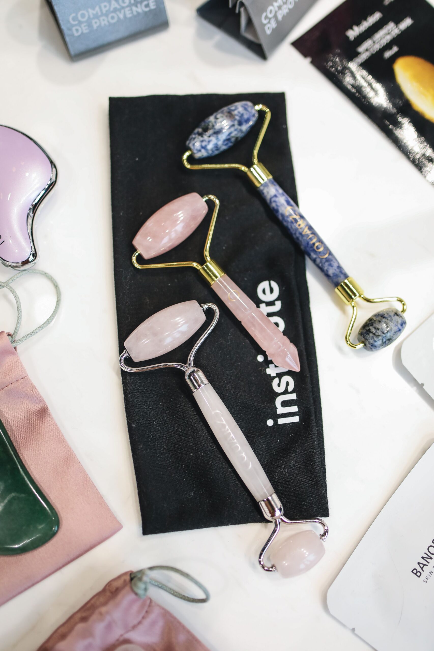 A variety of luxurious facial rollers, including rose quartz, showcased on a table for skincare enthusiasts.